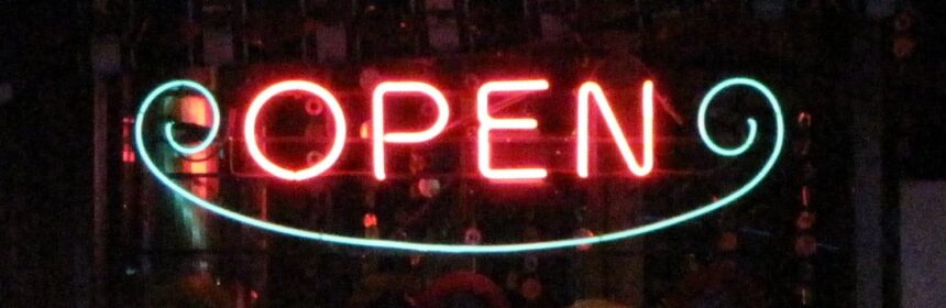 Pink and blue neon open sign against a black background