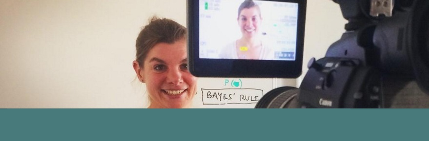 Woman standing in front of a whiteboard being recorded on a professional video camera