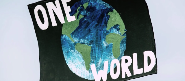 sign with text One World over painting of the earth