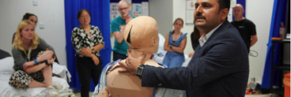 A man demonstrates with a dummy to a group of students in a medical room