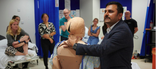 A man demonstrates with a dummy to a group of students in a medical room
