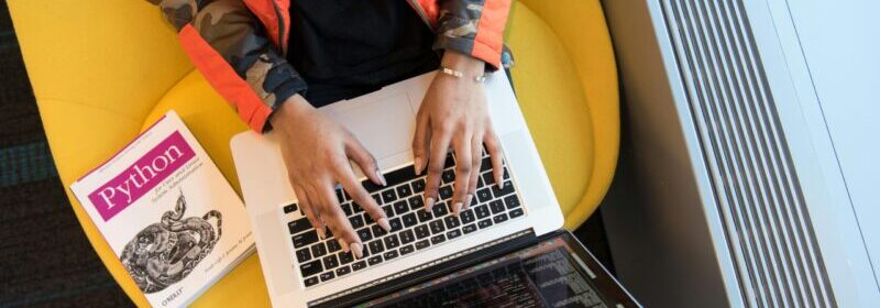 prson using macbook pro and a python coding book